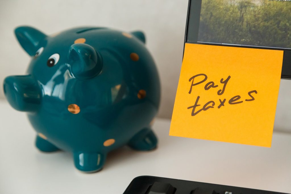 a piggy bank and a note that says pay taxes