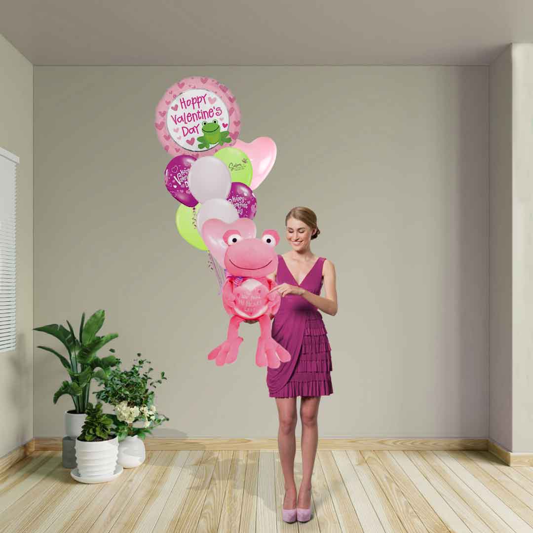 Young girl holding a Valentine's Day helium balloon bouquet with a large pink frog plush with a "You make my heart leap" embroidered message. Salem Oregon Balloon delivery.