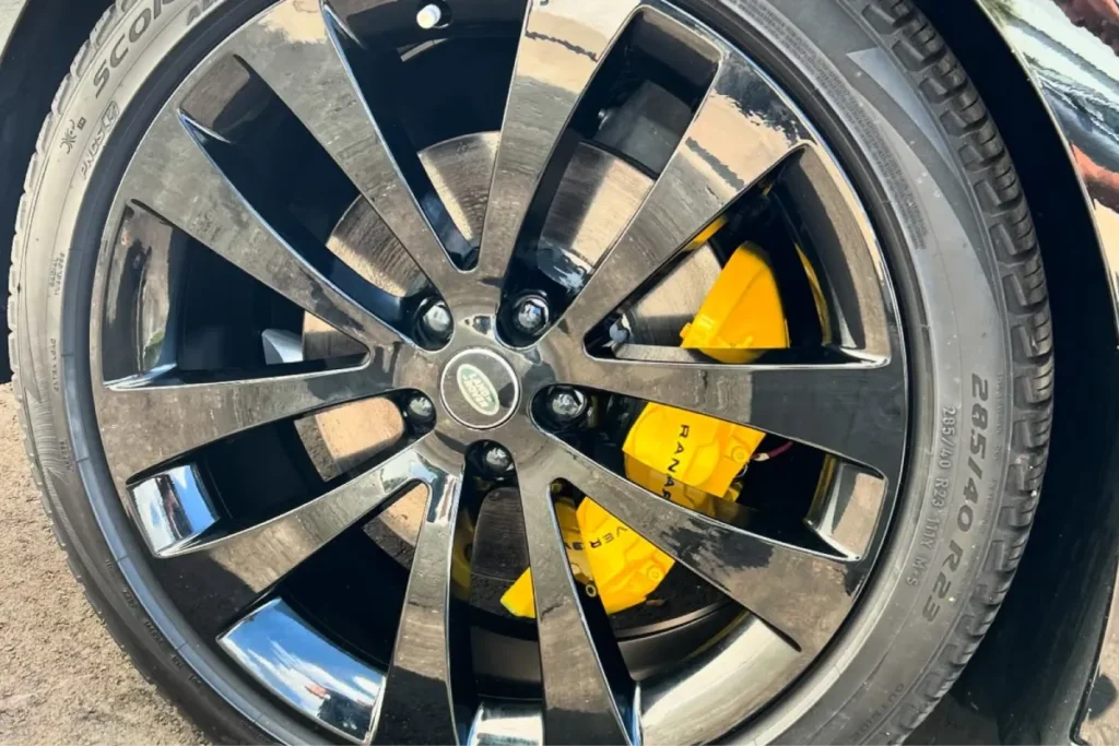 Bright yellow brake calipers visible behind a chrome wheel after professional brake caliper painting.
