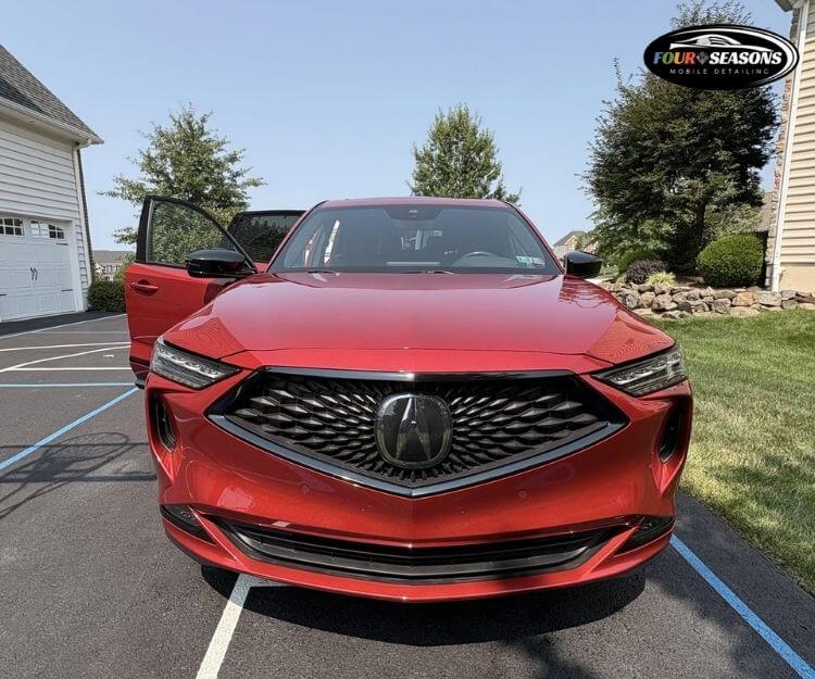 Front view of a red Acura SUV parked in a paved lot with driver's side door open.