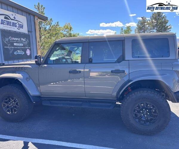 Side profile of a gray off-road SUV parked outdoors on an asphalt surface.