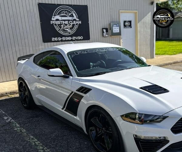 Close-up front quarter view of a white sports car parked outside a building.